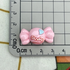 Detailed close-up of a pink resin candy charm with Candy text and heart icon on a cutting mat