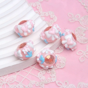 Detail of pink hand-painted craft beads with white floral patterns and blue accents