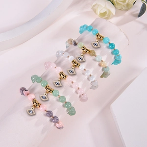 Close-up of colorful 8mm stone bead bracelets featuring blue evil eye charms on a stand