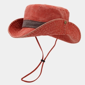 Detail of red washed canvas hiking hat with brown strap, metal buckle and windproof cord