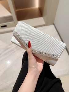 Elegant white pleated evening clutch bag with rhinestone strap held by hand