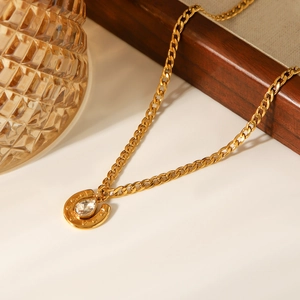 Detail of 18k gold plated Cuban chain necklace with zircon horseshoe pendant on a tray