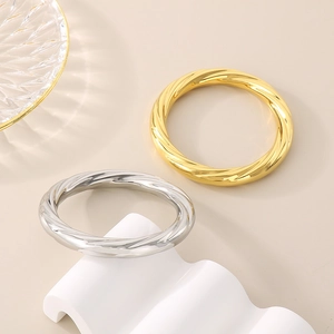 Twisted spiral stainless steel rings in gold and silver finish on artistic wavy display