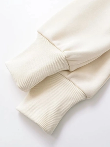 Detail of cream white fleece hoodie showing high-quality ribbed cuff and soft knit texture
