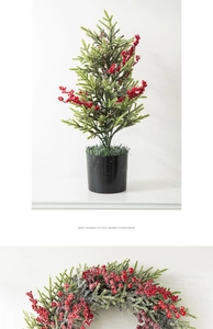 Detail of green pine needles and red berries in a black matte pot for Christmas decor