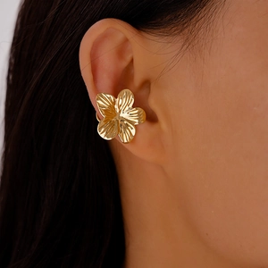 Detailed view of a golden five-petal flower ear cuff with textured metal petals on ear