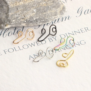 Detailed collection of fake nose rings in five metallic finishes on textured background