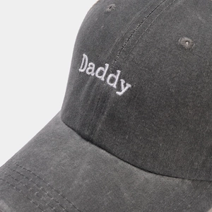 Detailansicht der weißen Daddy-Stickerei auf einer dunkelgrauen Baumwoll-Basecap