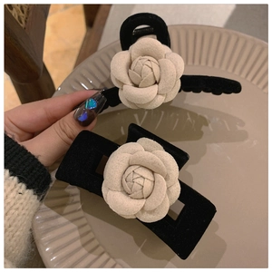 Macro detail of vintage black velvet hair claw clips with white camellia flower decoration
