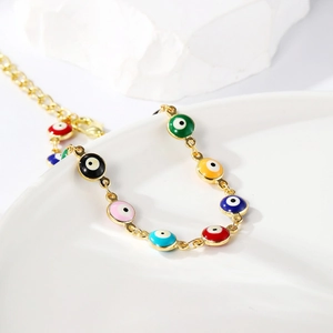 Detail of colorful enamel evil eye charms on a gold bohemian pull chain bracelet