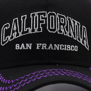 Detailed close-up of white letter embroidery on black cotton baseball cap fabric
