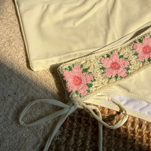 Detail of cream bikini featuring handmade pink crochet flower trim and side tie design