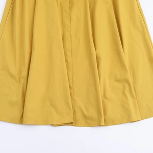 Gros plan sur la texture du tissu de la robe midi jaune et les coutures de l'ourlet