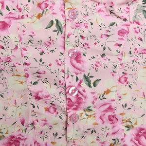 Close-up of pink floral fabric with rose patterns and delicate round buttons detail