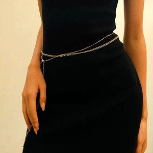 Detail of layered gold body chain with beads on a black dress for bohemian beach style
