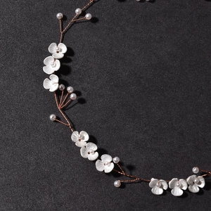 Detailed close-up of handmade bridal headband with white flowers and pearls on copper wire