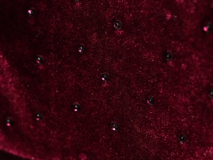 Dettaglio macro del tessuto in velluto rosso scuro con strass neri scintillanti