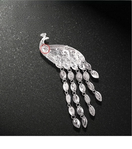 Macro detail of silver peacock brooch pin with sparkling rhinestones and tassel charms