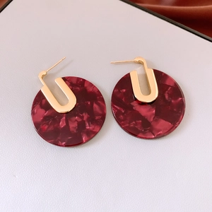 Detail of burgundy marble acetate earrings with gold U-shaped metal studs on leather