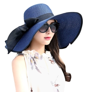 Navy blue wide brim straw sun hat with black bow and elegant wavy edge for beach travel