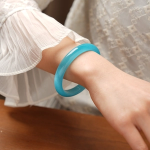 Polished bright blue cat eye stone bangle shown on model wrist with lace detailing