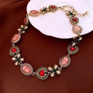 Vintage gold jewelry set with red heart gems and pink cameo pendants on white ceramic
