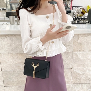 Chic black flap crossbody bag featuring golden deer head ornament and tassel detail