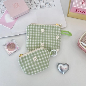 Detail of floral embroidery on green gingham fabric bags with pearl zipper charms