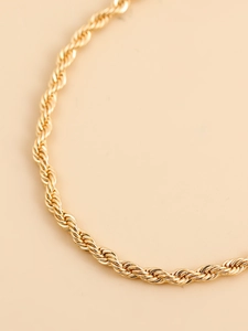 Macro shot of gold rope chain necklace featuring dense woven texture and metallic luster