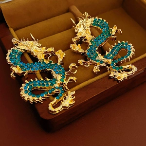 Dettaglio di orecchini a forma di drago placcati in oro con zirconi color verde petrolio