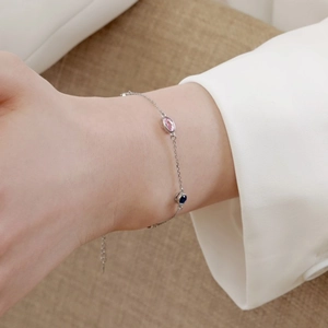 Detailed shot of S925 silver bracelet with pink and blue oval gemstones on a female wrist
