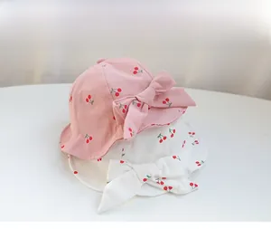 Detailed view of baby sun hats featuring cherry print and large decorative side bows