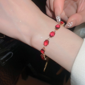Close-up of elegant gold bracelet with oval ruby-red stones and adjustable chain
