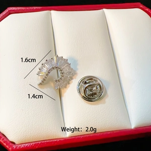 Macro view of silver feather brooch with clear gems, measuring 1.6cm by 1.4cm