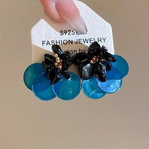 Detail of S925 silver needle earrings with black 3D flower and blue resin disc charm
