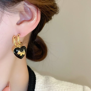 Macro shot of gold-plated hoop earrings with black enamel heart and dog pendant