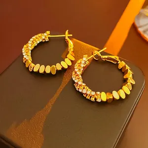 Detail of gold hoop earrings with sparkling zircon inlay and smooth metallic finish