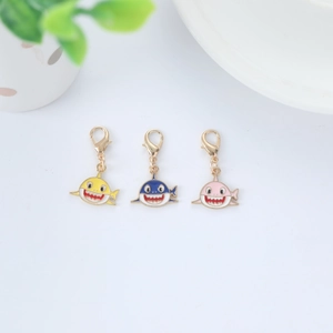Close-up of cute yellow, blue, and pink shark charms with gold-tone lobster clasps