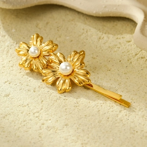 Golden flower hair clip with pearls on a textured background in a high-quality still shot
