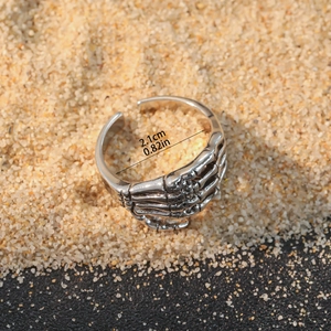 Gothic punk skeleton hand open ring in silver finish on sand background with size details