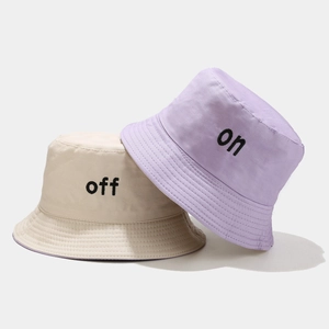 Détail de la broderie 'on' et 'off' sur les bobs en coton de couleur violette et beige