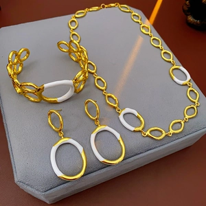 Detail view of gold and white enamel jewelry set including necklace, bracelet and earrings