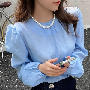 Detail of elegant sky blue round neck blouse with pleated collar and puff sleeves