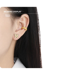 Close-up of butterfly stud earrings and wave textured ear cuff worn on the ear