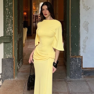 Detail of elegant pale yellow long dress showing pleated knot waist and draped fabric texture