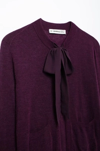 Détail du cardigan en maille prune élégant avec un nœud papillon chic au col et étiquette