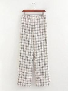 Detail of tweed trousers with black and white plaid pattern hanging on a wooden hanger