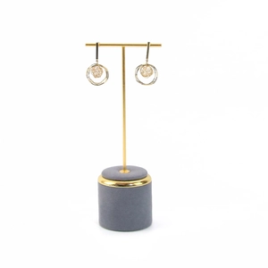 Golden T-bar jewelry stand with microfiber base displaying circular metal earrings