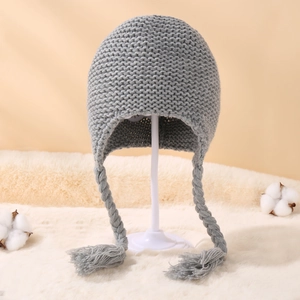 Detail of grey knitted baby winter hat with braids, tassels and warm fleece lining