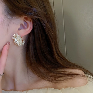 Elegant white acrylic flower C-hoop earrings with gold center worn by a model